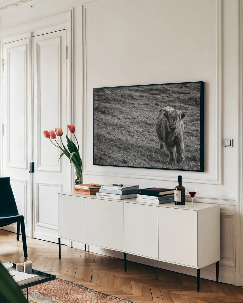 Highland Cow Calf in the Wind by Nathan Larson. shown as a framed stretched canvas in a living room above a console. Available as a archival giclee rolled canvas, fine art paper, or poster print. SKU 70523i.