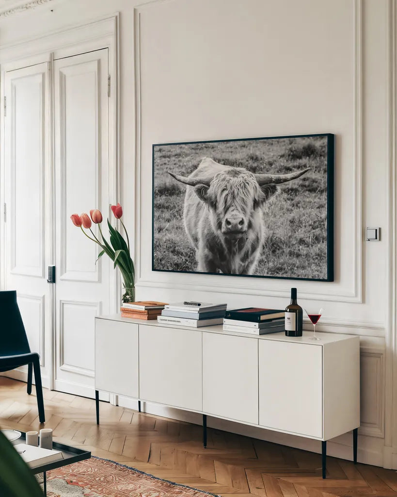 Highland Cow Staring Contest by Nathan Larson. shown as a framed stretched canvas in a living room above a console. Available as a archival giclee rolled canvas, fine art paper, or poster print. SKU 70280i.