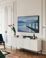 Lake McDonald Dock by Alan Majchrowicz. shown as a framed stretched canvas in a living room above a console. Available as a archival giclee rolled canvas, fine art paper, or poster print. SKU 43057i.