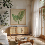 Monstera Leaves Neutral Crop by Albena Hristova. Shown in a natural wood frame in a cozy modern living room. Available as an archival giclee rolled canvas, fine art paper, or poster print. SKU 24274a.