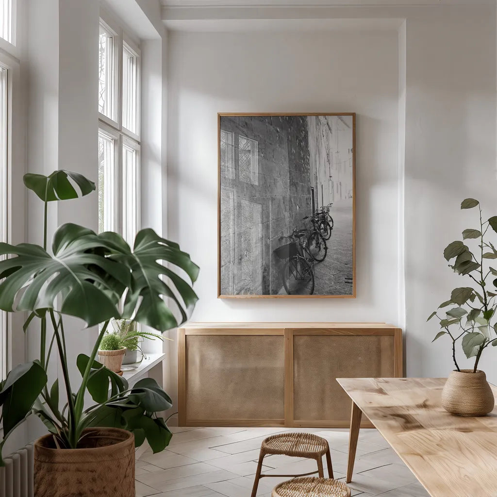 Bicycles in the Alley by Aledanda. shown as a print in a natural wood frame in a dining room. Available as a archival giclee rolled canvas, fine art paper, or poster print. SKU 67688h.
