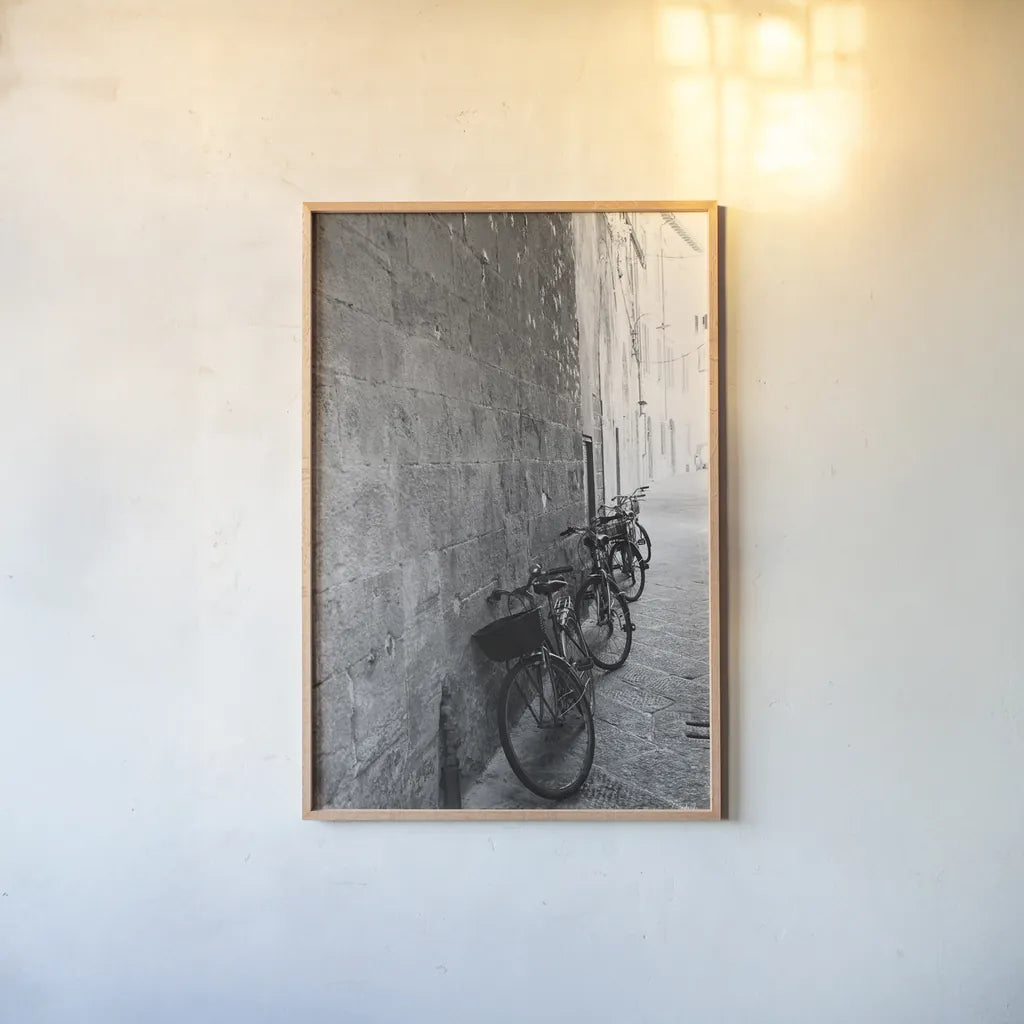 Bicycles in the Alley by Aledanda. shown as a paper print in a natural frame. Available as a archival giclee rolled canvas, fine art paper, or poster print. SKU 67688h.
