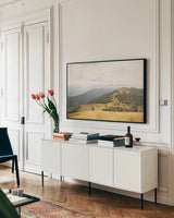 Grassy Hills and Mountains by Aledanda. shown as a framed stretched canvas in a living room above a console. Available as a archival giclee rolled canvas, fine art paper, or poster print. SKU 63229i.