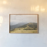 Grassy Hills and Mountains by Aledanda. shown as a paper print in a natural frame. Available as a archival giclee rolled canvas, fine art paper, or poster print. SKU 63229i.