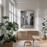 Village Square by Aledanda. shown as a print in a natural wood frame in a dining room. Available as a archival giclee rolled canvas, fine art paper, or poster print. SKU 67690h.