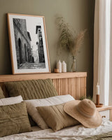 Village Square by Aledanda. shown as a paper print in a natural frame. Available as a archival giclee rolled canvas, fine art paper, or poster print. SKU 67690h.