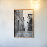 Village Square by Aledanda. shown as a paper print in a natural frame. Available as a archival giclee rolled canvas, fine art paper, or poster print. SKU 67690h.