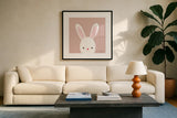 Cuddly Bunny Soft Pink by Ann Kelle. Displayed in a glass frame with matte in a clean modern living room. Available as an archival giclee rolled canvas, fine art paper, or poster print. SKU 62025a.