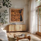 Black Cats and Witches Hats I by Anne Tavoletti. Shown in a natural wood frame in a cozy modern living room. Available as an archival giclee rolled canvas, fine art paper, or poster print. SKU 73732a.