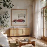 Roadster I Red Car by Avery Tillmon. Shown in a natural wood frame in a cozy modern living room. Available as an archival giclee rolled canvas, fine art paper, or poster print. SKU 53125a.