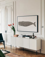 Whale on White by Avery Tillmon. shown as a framed stretched canvas in a living room above a console. Available as a archival giclee rolled canvas, fine art paper, or poster print. SKU 65529i.