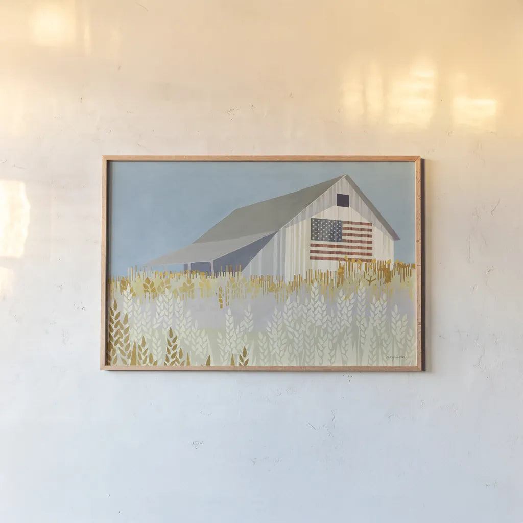 Wheat Fields Barn with Flag by Avery Tillmon. shown as a paper print in a natural frame. Available as a archival giclee rolled canvas, fine art paper, or poster print. SKU 76408i.