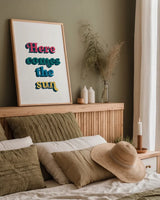 Rainbow Here Comes the Sun Bold by Becky Thorns. shown as a paper print in a natural frame. Available as a archival giclee rolled canvas, fine art paper, or poster print. SKU 65214h.