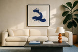 Cobalt Ink Drops II by Chris Paschke. Displayed in a glass frame with matte in a clean modern living room. Available as an archival giclee rolled canvas, fine art paper, or poster print. SKU 67369a.
