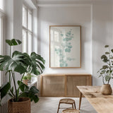 Eucalyptus Branch II by Chris Paschke. shown as a print in a natural wood frame in a dining room. Available as a archival giclee rolled canvas, fine art paper, or poster print. SKU 55064h.