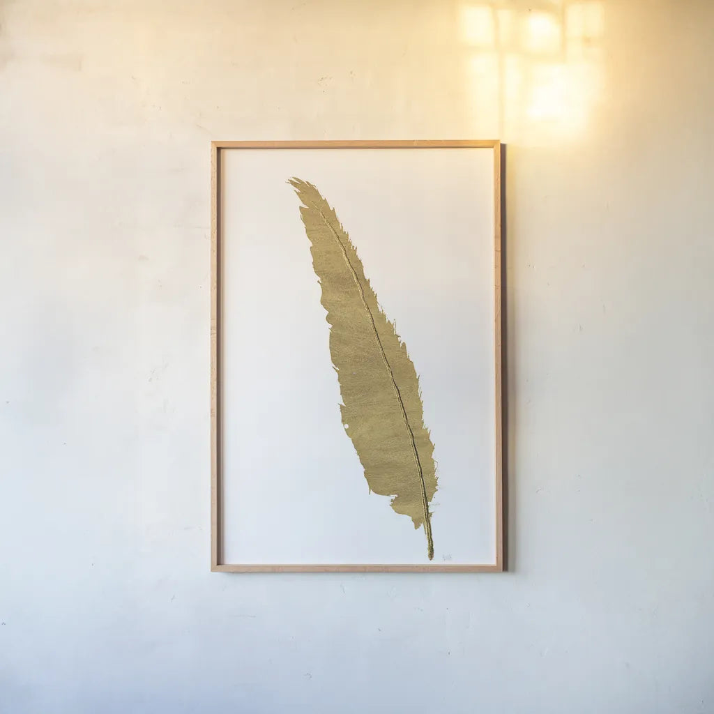 Pure Gold Feather VI by Chris Paschke. shown as a paper print in a natural frame. Available as a archival giclee rolled canvas, fine art paper, or poster print. SKU 28004h.