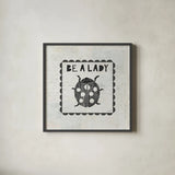 Ladybug Stamp Be A Lady by Courtney Prahl. Shown in a sleek black glass frame for a contemporary gallery look. Available as an archival giclee rolled canvas, fine art paper, or poster print. SKU 52084a.
