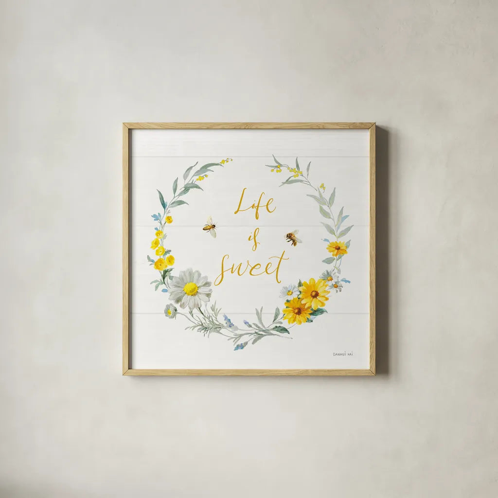 Bees and Blooms_Life is Sweet Wreath by Danhui Nai. Shown in a natural wood glass frame for a timeless modern aesthetic. Available as an archival giclee rolled canvas, fine art paper, or poster print. SKU 78405a.