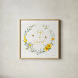 Bees and Blooms_Life is Sweet Wreath by Danhui Nai. Shown in a natural wood glass frame for a timeless modern aesthetic. Available as an archival giclee rolled canvas, fine art paper, or poster print. SKU 78405a.