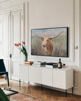 Big Sky Longhorn Sunset by Danhui Nai. shown as a framed stretched canvas in a living room above a console. Available as a archival giclee rolled canvas, fine art paper, or poster print. SKU 76005i.