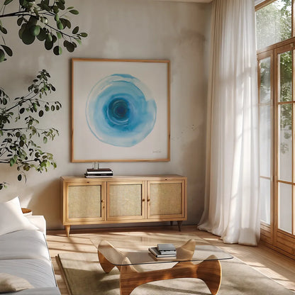 Center of Blue I by Danhui Nai. Shown in a natural wood frame in a cozy modern living room. Available as an archival giclee rolled canvas, fine art paper, or poster print. SKU 76093a.