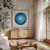 Center of Blue II by Danhui Nai. Shown in a natural wood frame in a cozy modern living room. Available as an archival giclee rolled canvas, fine art paper, or poster print. SKU 76094a.