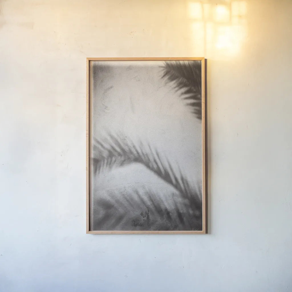 Palm Shadow Afternoon I by Deborah Revell. shown as a paper print in a natural frame. Available as a archival giclee rolled canvas, fine art paper, or poster print. SKU 94352h.