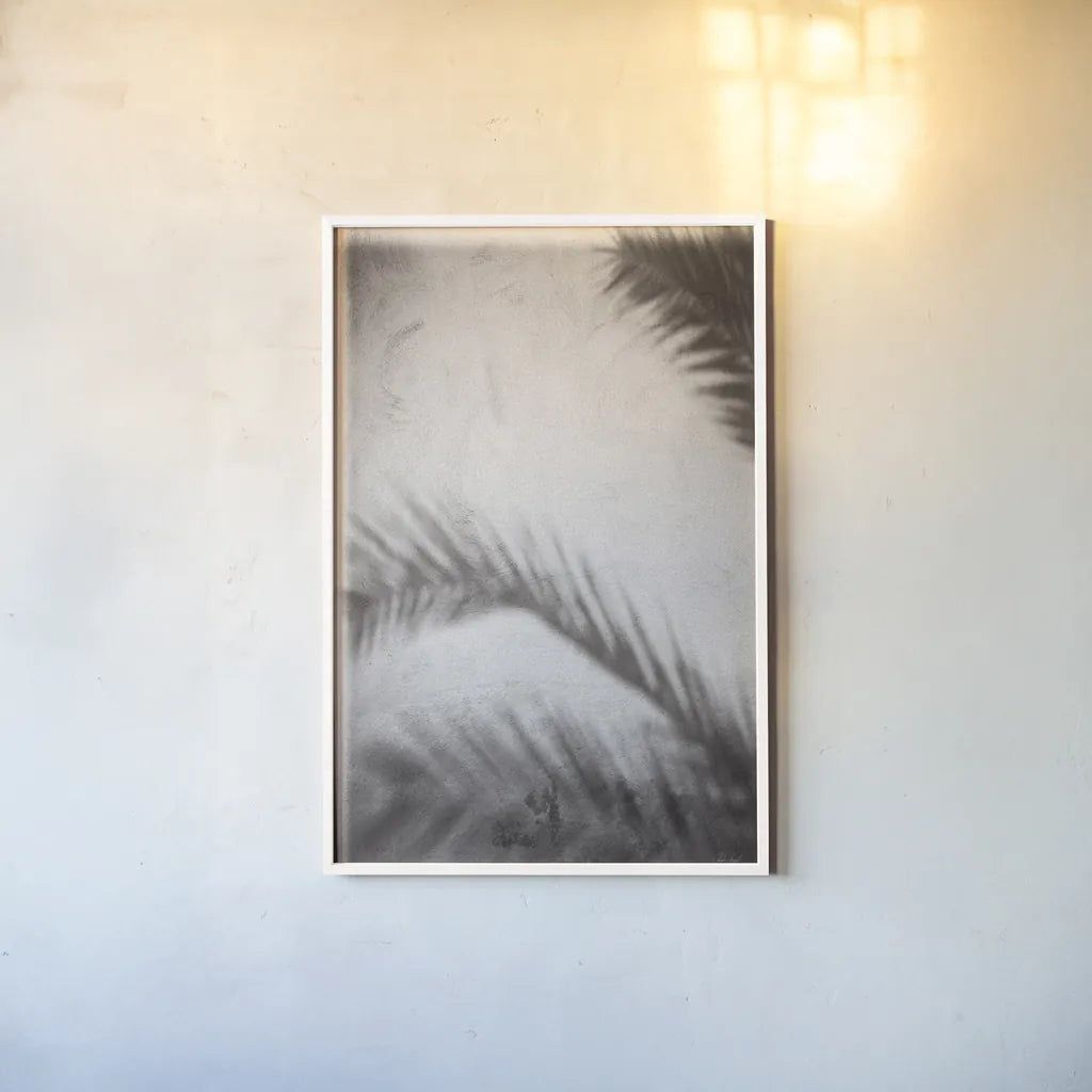 Palm Shadow Afternoon I by Deborah Revell. shown as a paper print in a white frame. Available as a archival giclee rolled canvas, fine art paper, or poster print. SKU 94352h.