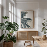 Tropical Palm I by Deborah Revell. shown as a print in a natural wood frame in a dining room. Available as a archival giclee rolled canvas, fine art paper, or poster print. SKU 104962h.