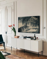 Tropical Palm III by Deborah Revell. shown as a framed stretched canvas in a living room above a console. Available as a archival giclee rolled canvas, fine art paper, or poster print. SKU 104964i.