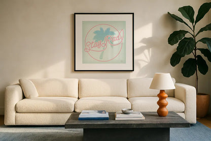 Stay Rad Palm I by Dina June. Displayed in a glass frame with matte in a clean modern living room. Available as an archival giclee rolled canvas, fine art paper, or poster print. SKU 64943a.