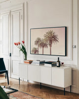 Pastel Palms by Elizabeth Urquhart. shown as a framed stretched canvas in a living room above a console. Available as a archival giclee rolled canvas, fine art paper, or poster print. SKU 67332i.