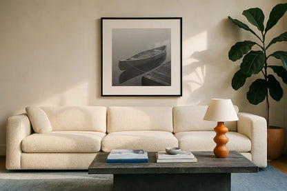 Calm Waters Canoe II BW by Jess Aiken. Displayed in a glass frame with matte in a clean modern living room. Available as an archival giclee rolled canvas, fine art paper, or poster print. SKU 83656a.
