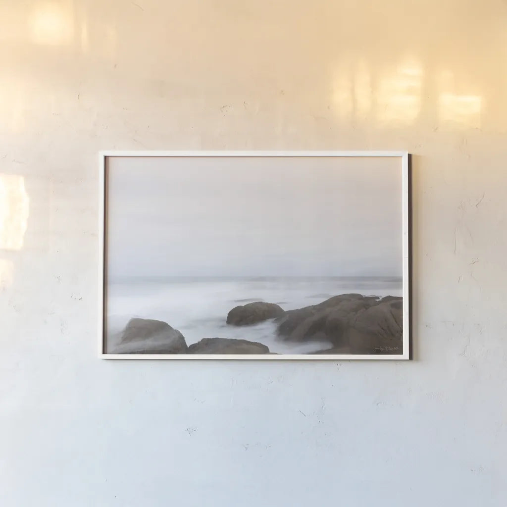 Misty Shore on the Rocks by Jocelyn Elizabeth. shown as a paper print in a white frame. Available as a archival giclee rolled canvas, fine art paper, or poster print. SKU 100324i.