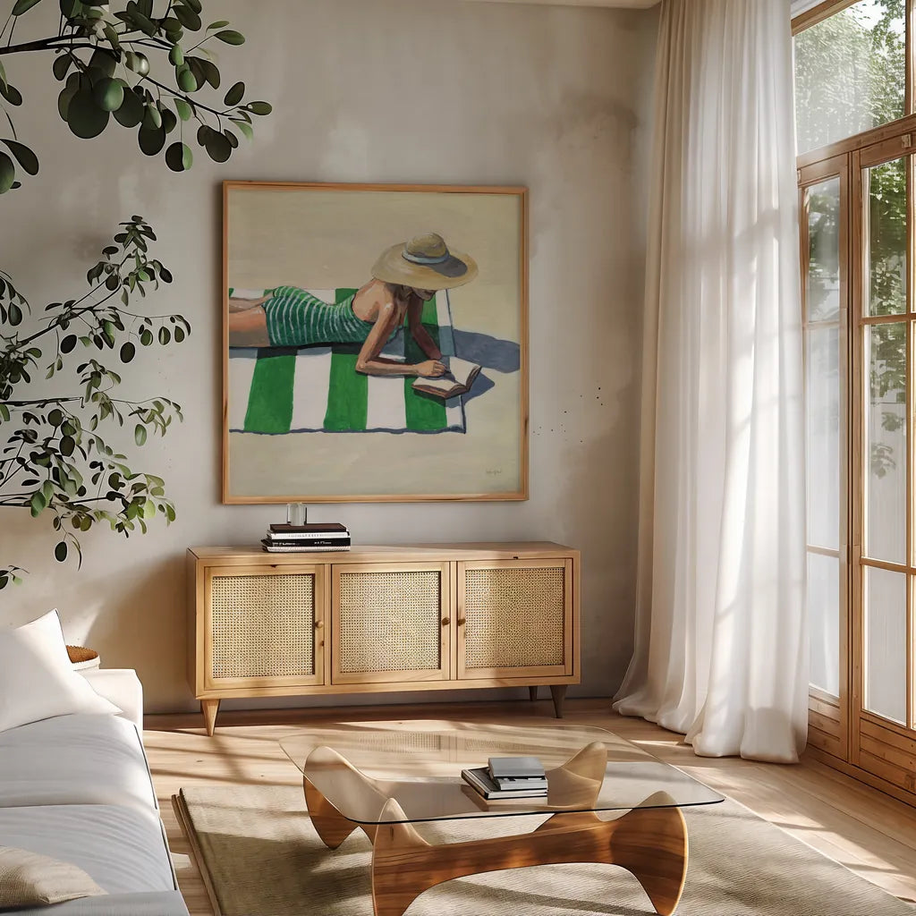 Reading at The Beach v2 by Kate Jarvik Birch. Shown in a natural wood frame in a cozy modern living room. Available as an archival giclee rolled canvas, fine art paper, or poster print. SKU 100782a.