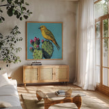 Yellow Bird on Cacti Bloom by Kate Jarvik Birch. Shown in a natural wood frame in a cozy modern living room. Available as an archival giclee rolled canvas, fine art paper, or poster print. SKU 98543a.