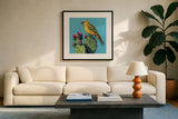Yellow Bird on Cacti Bloom by Kate Jarvik Birch. Displayed in a glass frame with matte in a clean modern living room. Available as an archival giclee rolled canvas, fine art paper, or poster print. SKU 98543a.