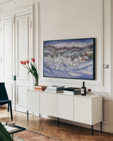 Winter Village by Kathleen Parr McKenna. shown as a framed stretched canvas in a living room above a console. Available as a archival giclee rolled canvas, fine art paper, or poster print. SKU 80802i.