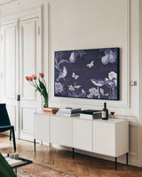 Botanical Blue IV by Katie Pertiet. shown as a framed stretched canvas in a living room above a console. Available as a archival giclee rolled canvas, fine art paper, or poster print. SKU 42175i.