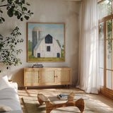 Little White Barn by Krystal Adams. Shown in a natural wood frame in a cozy modern living room. Available as an archival giclee rolled canvas, fine art paper, or poster print. SKU 102220a.