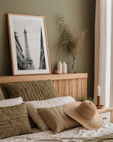 Eiffel Glimpse by Laura Marshall. shown as a paper print in a natural frame. Available as a archival giclee rolled canvas, fine art paper, or poster print. SKU 25887h.