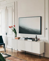 Virgin Mountains II Blue Gray by Laura Marshall. shown as a framed stretched canvas in a living room above a console. Available as a archival giclee rolled canvas, fine art paper, or poster print. SKU 79233i.