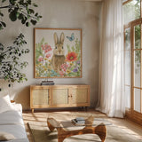 Garden Bunnies III by Leslie Trimbach. Shown in a natural wood frame in a cozy modern living room. Available as an archival giclee rolled canvas, fine art paper, or poster print. SKU 83603a.