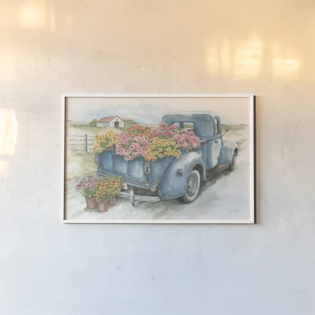 Truck with Flowers on Blue by Leslie Trimbach. shown as a paper print in a white frame. Available as a archival giclee rolled canvas, fine art paper, or poster print. SKU 86547i.