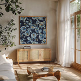Indigold Flower Toss Indigo by Lisa Audit. Shown in a natural wood frame in a cozy modern living room. Available as an archival giclee rolled canvas, fine art paper, or poster print. SKU 33664a.