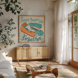 Love Keeps Us Together Orange by Mary Urban. Shown in a natural wood frame in a cozy modern living room. Available as an archival giclee rolled canvas, fine art paper, or poster print. SKU 30512a.