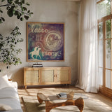Universe Galaxy Lasso the Moon Sq by Mary Urban. Shown in a natural wood frame in a cozy modern living room. Available as an archival giclee rolled canvas, fine art paper, or poster print. SKU 18443a.