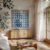 Kanari Square I Indigo by Melissa Averinos. Shown in a natural wood frame in a cozy modern living room. Available as an archival giclee rolled canvas, fine art paper, or poster print. SKU 43111a.