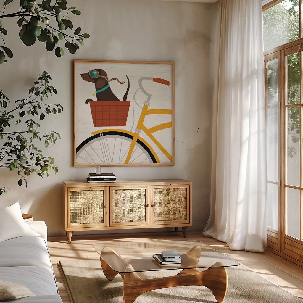 Beach Bums Dachshund Bicycle I by Michael Mullan. Shown in a natural wood frame in a cozy modern living room. Available as an archival giclee rolled canvas, fine art paper, or poster print. SKU 23291a.