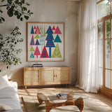 Geometric Holiday Trees II Bright by Michael Mullan. Shown in a natural wood frame in a cozy modern living room. Available as an archival giclee rolled canvas, fine art paper, or poster print. SKU 56253a.